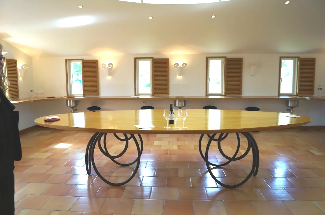 2013-04-29に酒井 浩（プラチナワイン（有限会社デリバリー・ワイン）代表）がシャトー・ムートン・ロートシルト / Pauillac, Médoc, Bordeaux, Franceで撮影したシャトー・ムートン・ロートシルトを象徴する楕円形テイスティングテーブル。錬鉄の円環を複雑に組み合わせた脚とブロンド材の一枚板天板が特徴で、天窓からの自然光と木製