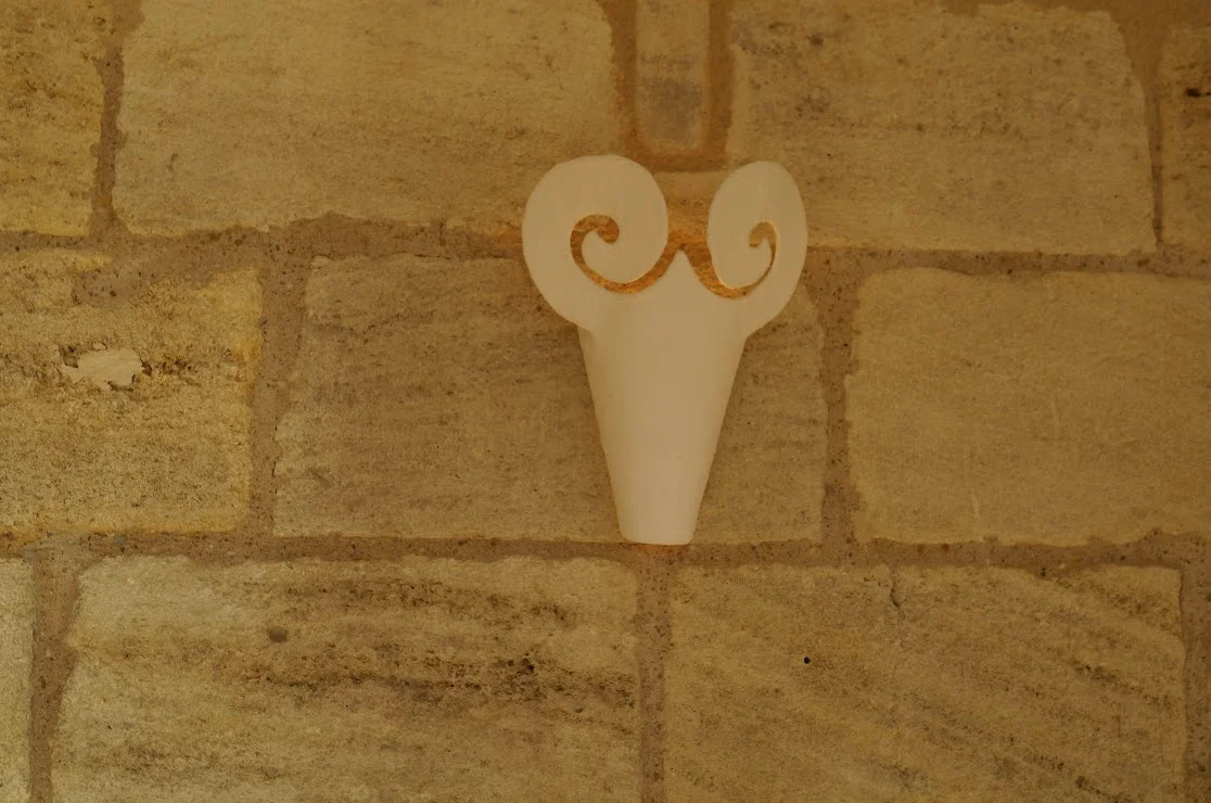 2013-04-29に酒井 浩（プラチナワイン（有限会社デリバリー・ワイン）代表）がシャトー・ムートン・ロートシルト / Pauillac, Médoc, Bordeaux, Franceで撮影したシャトー内の石壁に掲げられた雄羊（ムートン）の角を持つ石灰岩の頭部レリーフ。「ムートン」の名と紋章に由来する象徴的装飾で、一級昇格後にフィリップ男爵が各所に配し